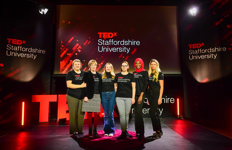 The Ted x Staffordshire University team wearing branded t-shirts on stage.
